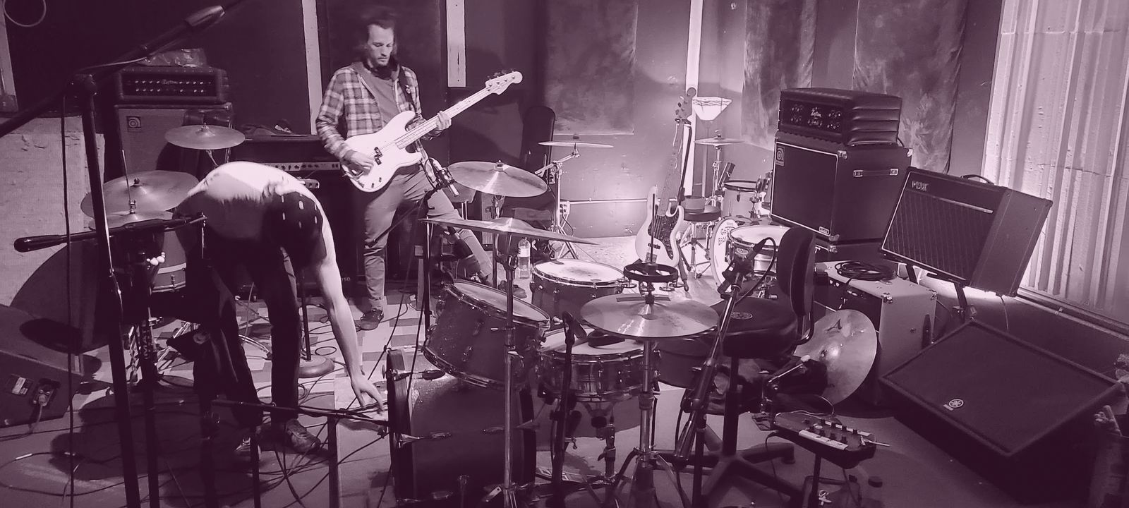 Russ Allen playing bass guitar on stage with his band.