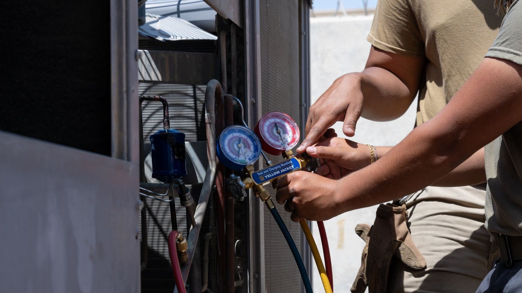 HVAC technicians reading refrigerant gauges on a condensing unit
