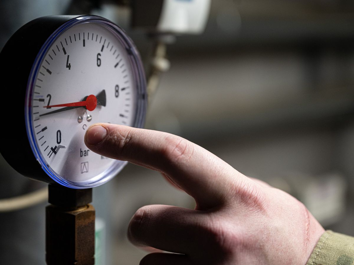 Hand pointing at a pressure gauge on HVAC equipment