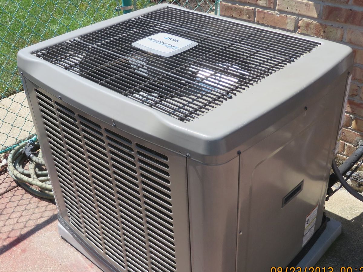 Residential central air conditioning condenser beside a house