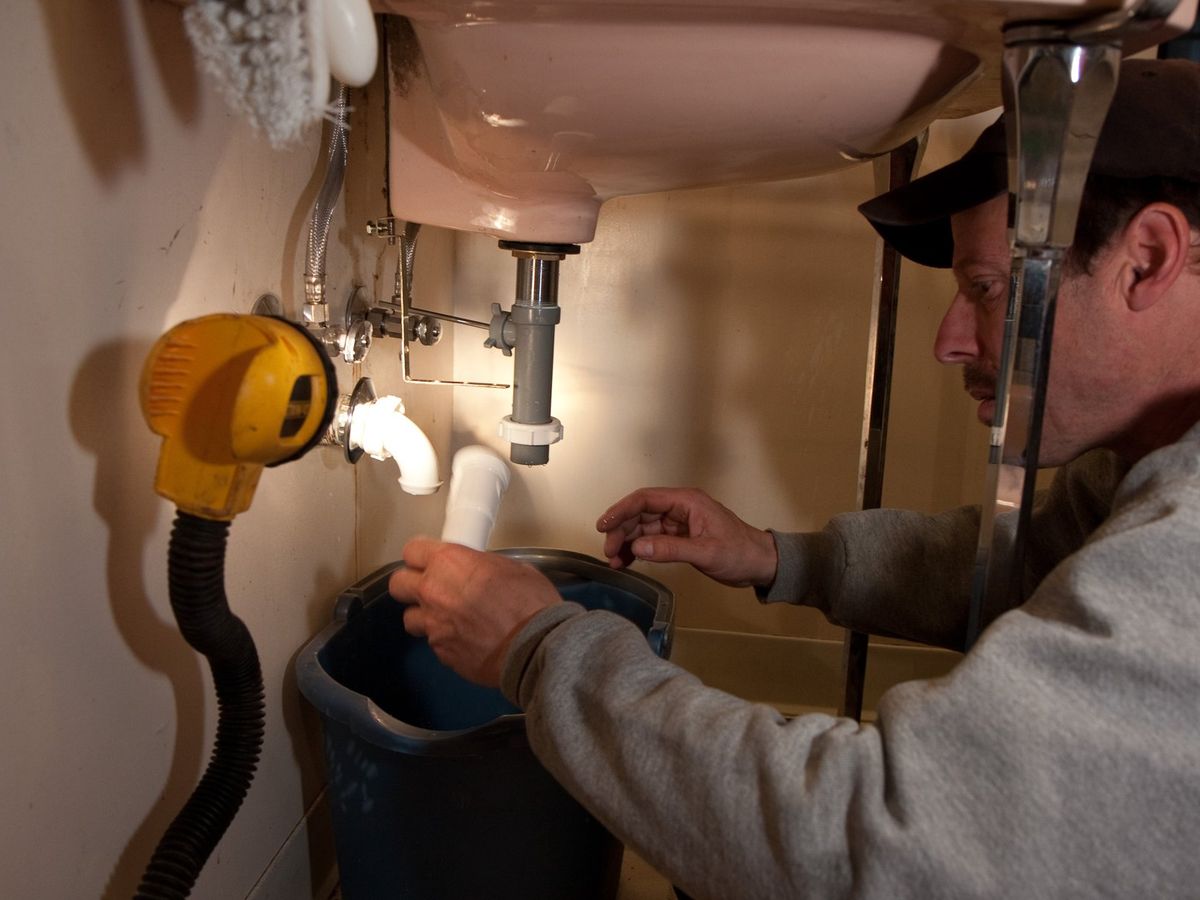 Plumber working under a bathroom sink