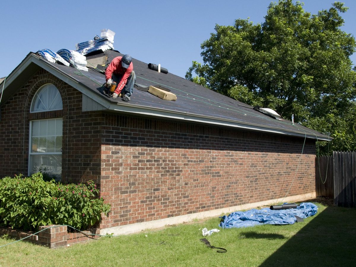 Roofer working on the roof of a brick house