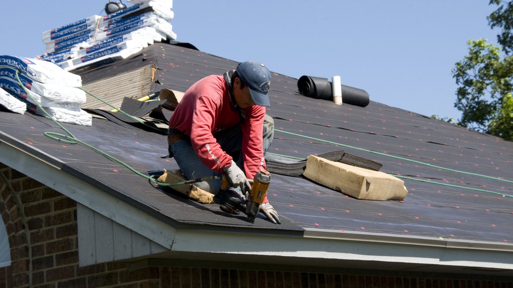 Roofer laying asphalt shingles on a house
