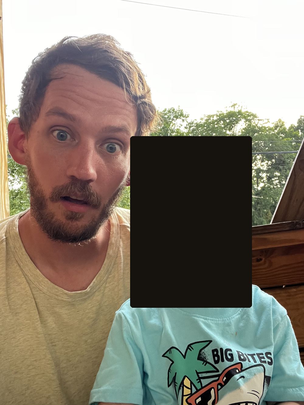 Russ Allen on a porch beside his young son, whose face is covered by a solid black block.