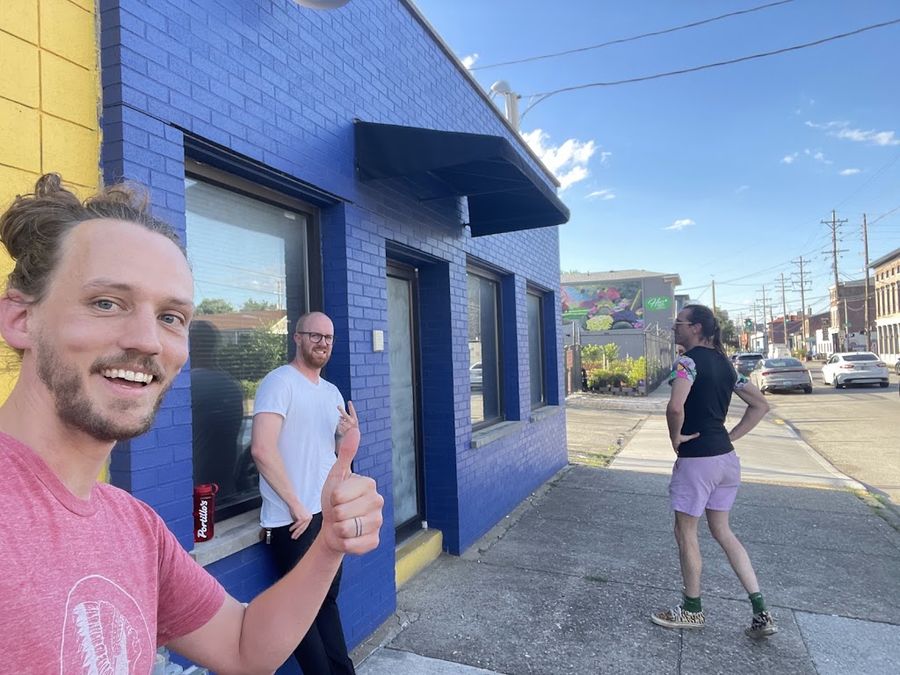 Thumbs up, outside a very blue building.
